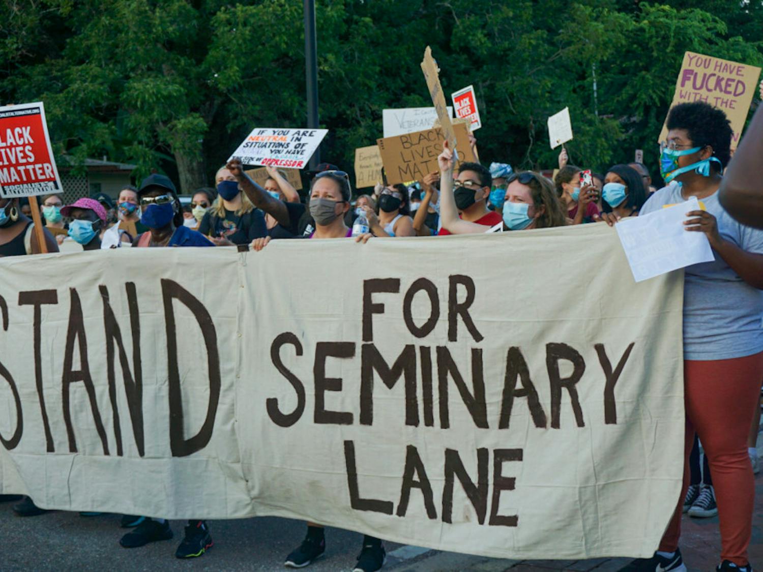 Protesters hold a banner that reads, "#StandForSeminaryLane," demanding that developers refrain from building luxury student apartments on land located in a historically Black community. 