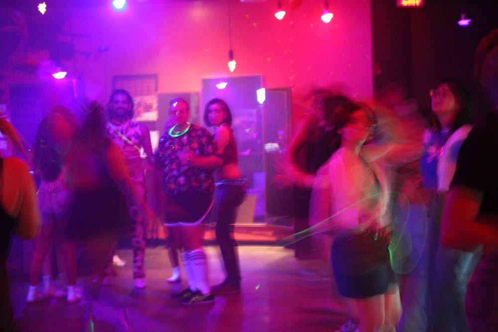 <p> Attendees dance under the neon lights of the How Bazar at Saturday’s event. </p>