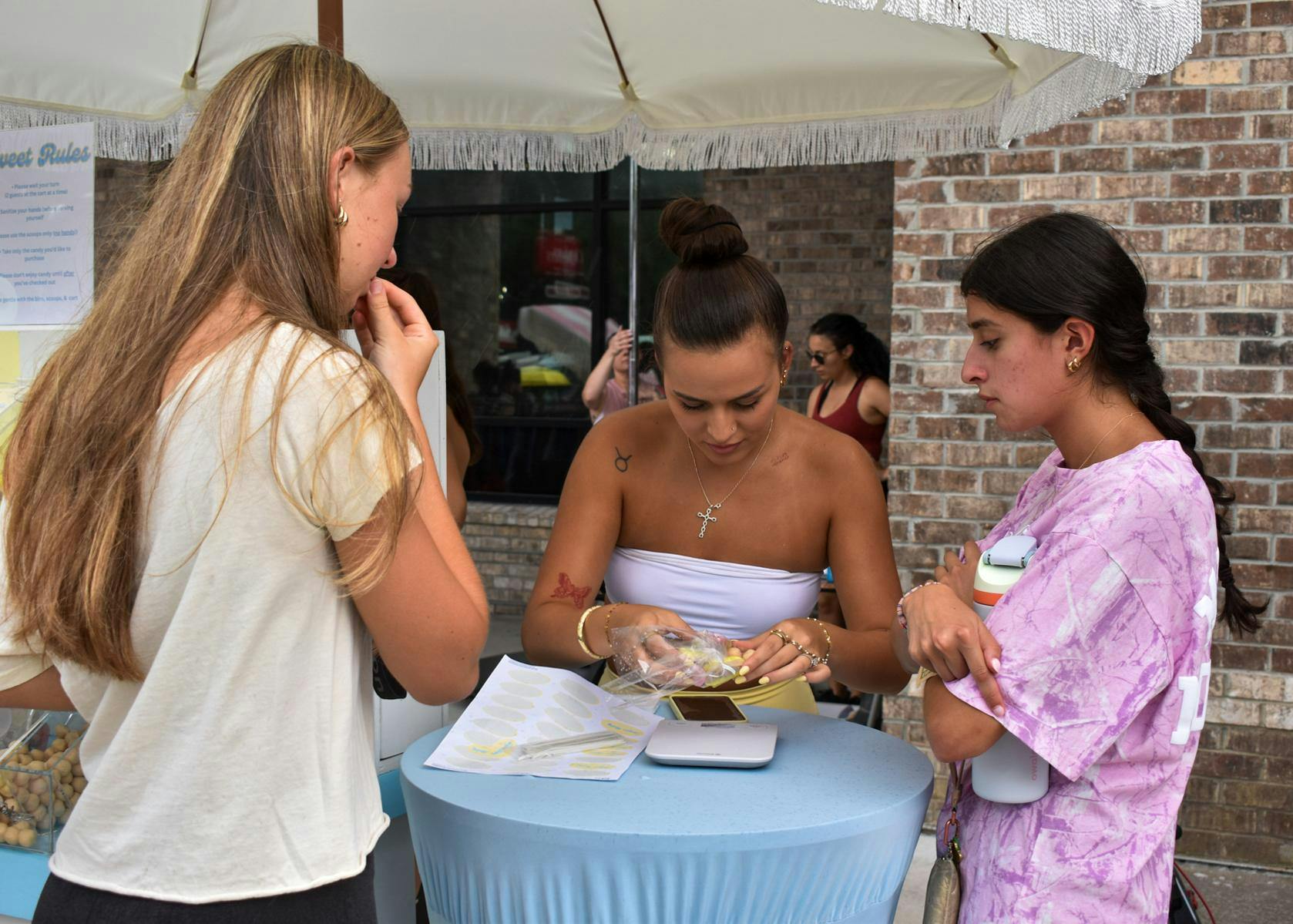 Customers purchase candies from the Sugar Baby Candy Cart at Peach by Pump's pop up Wednesday, Aug. 26, 2026 in Gainesville, Fla. 