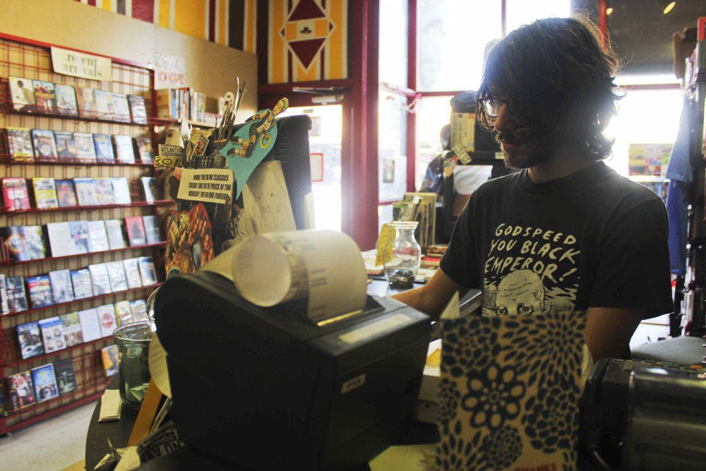 Ben Knazick, 24-year-old co-owner of Video Rodeo on West University Avenue, works at the store on Monday afternoon. The store will be moving to 10 E. University Ave.