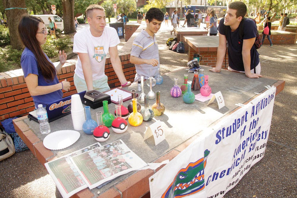 From left, McKenzie Caughlin, 21, Nick Lee, 19, Zared Schwartz,19, and Eliot Gunn, 19, members of the chemistry department sell painted flasks Monday, September 15 at Turlington Plaza to raise money for Paws on Parole. The group helps rehabilitate abused dogs.