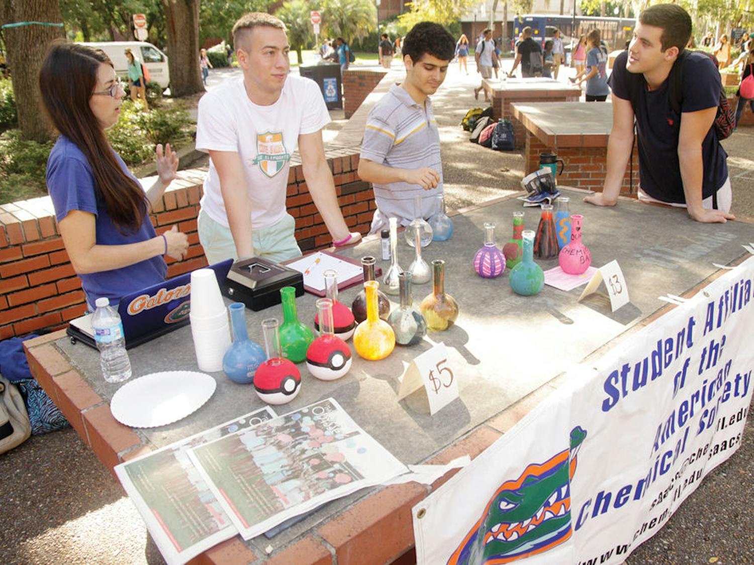 From left, McKenzie Caughlin, 21, Nick Lee, 19, Zared Schwartz,19, and Eliot Gunn, 19, members of the chemistry department sell painted flasks Monday, September 15 at Turlington Plaza to raise money for Paws on Parole. The group helps rehabilitate abused dogs.