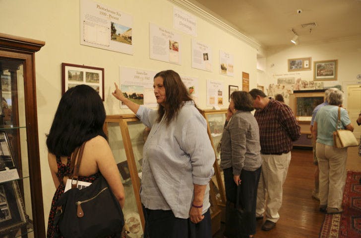 Matheson Museum volunteer Sharon Bauer, right, tells UF student Erika Hagarty, 23, about her favorite postcard on display at the gallery.