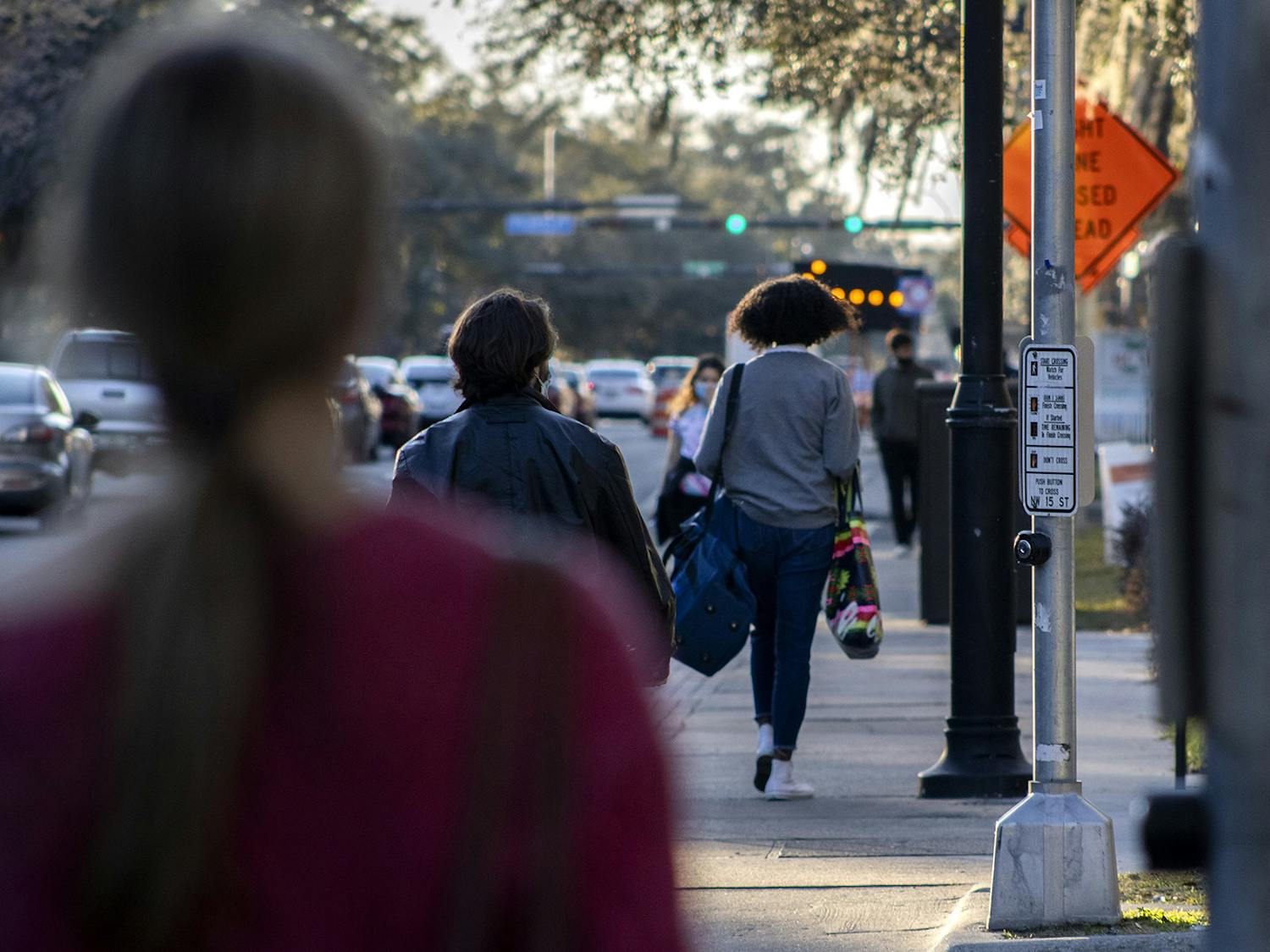 Pedestrians walk down West University Avenue on Wednesday, Feb. 3, 2021. Signs down the road redirect traffic due to ongoing construction on the road, near UF campus and Midtown.