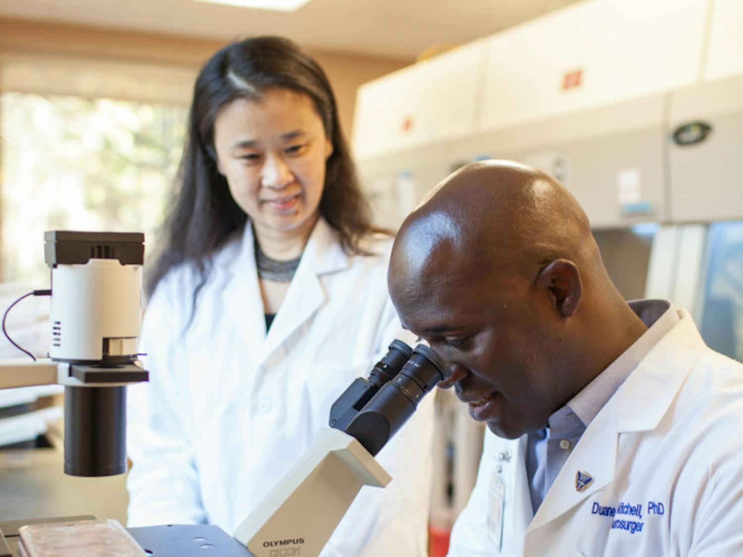 Duane Mitchell and Dr. Jianping Huang, Director of Clinical Laboratory Operations for the UF Brain Tumor Immunotherapy Program, work together on research in a laboratory. 