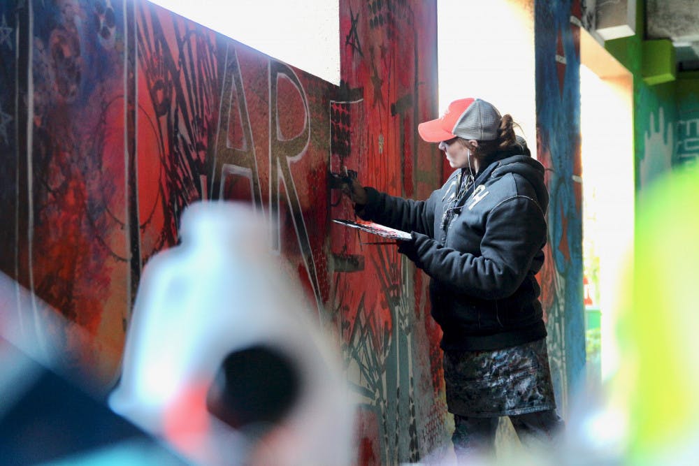 Alachua artist Sarah Whitmire, 37, participates in the beautification of a municipal parking lot located at 105 SW 3rd Street by painting a mural whose working title is: You are the Magic.
