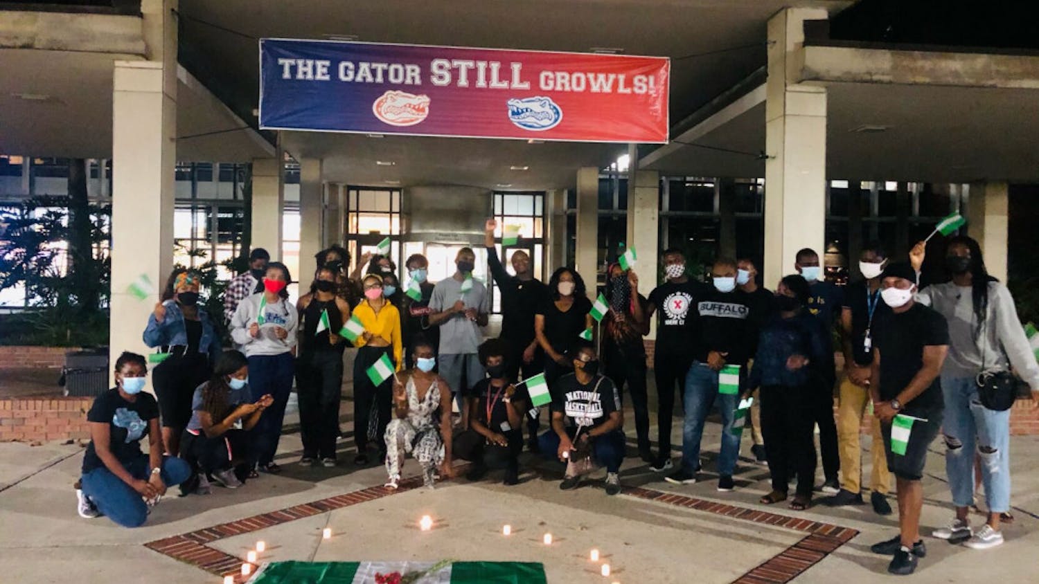 Masked UF students with Nigerian flags in hand stand in solidarity against police brutality in Nigeria and other forms of injustice throughout the continent. 