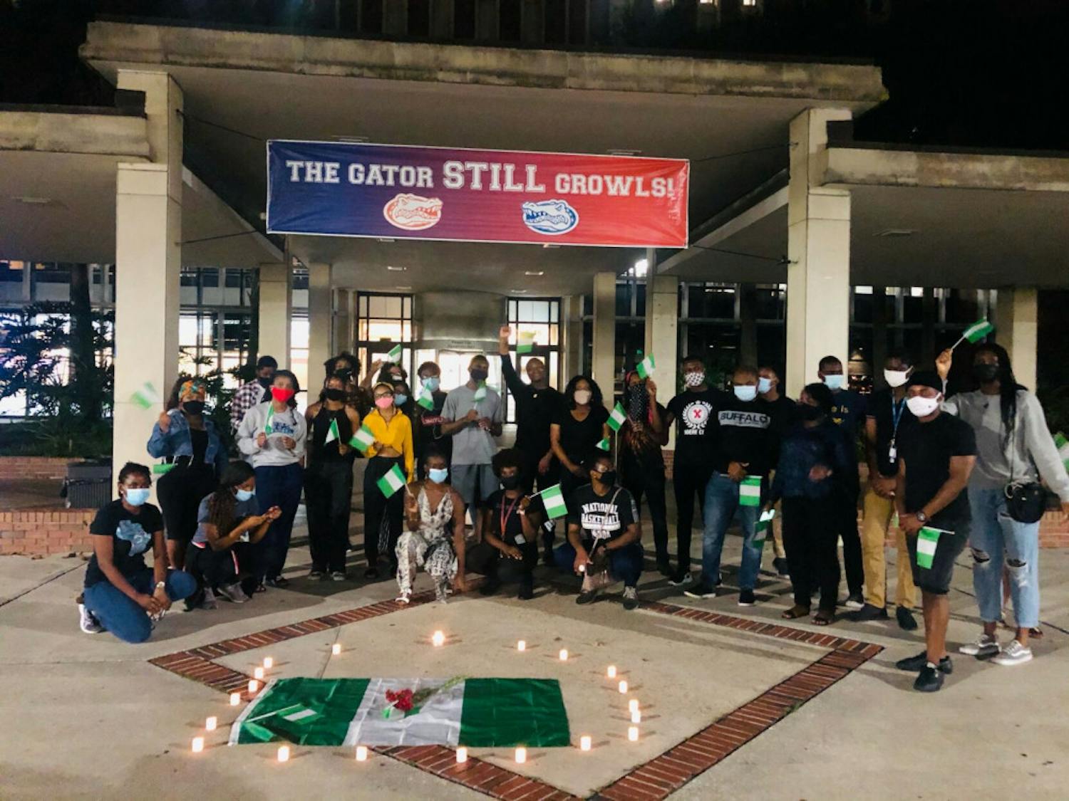 Masked UF students with Nigerian flags in hand stand in solidarity against police brutality in Nigeria and other forms of injustice throughout the continent.&nbsp;