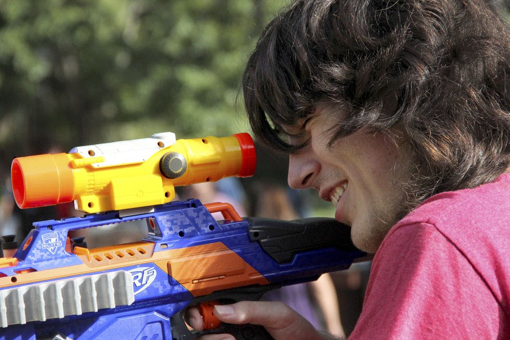 Mateo Vasquez, a 20-year-old sophomore, peers through the lens of his Nerf gun on Turlington Plaza on Tuesday afternoon. He was encouraging students to join Humans vs. Zombies, a five-day game of survival.