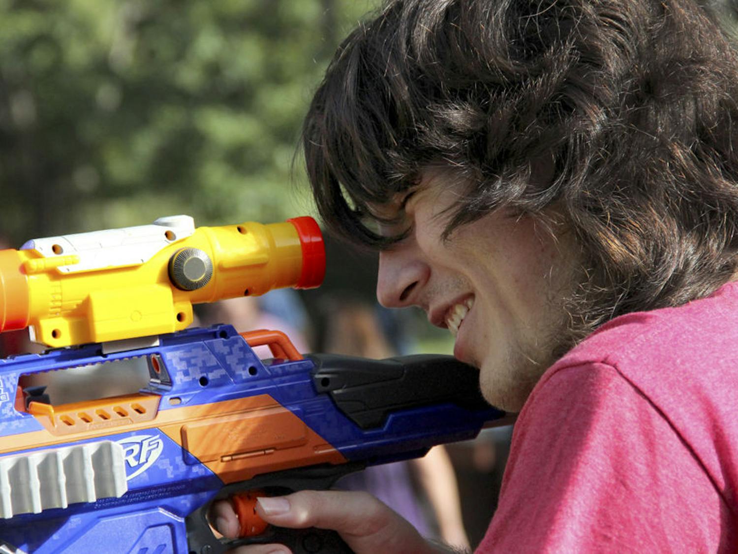 Mateo Vasquez, a 20-year-old sophomore, peers through the lens of his Nerf gun on Turlington Plaza on Tuesday afternoon. He was encouraging students to join Humans vs. Zombies, a five-day game of survival.