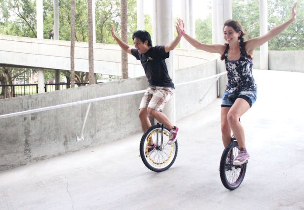 <p>UF alumnus PJ Arroyo, 24, rides a unicycle down a slope with Florida State University senior Maria Vaccaro, 21, at the Gainesville Unicycle Fest on Saturday. The festival included events such as races, hockey, limbo and football, all balanced on one wheel.</p>