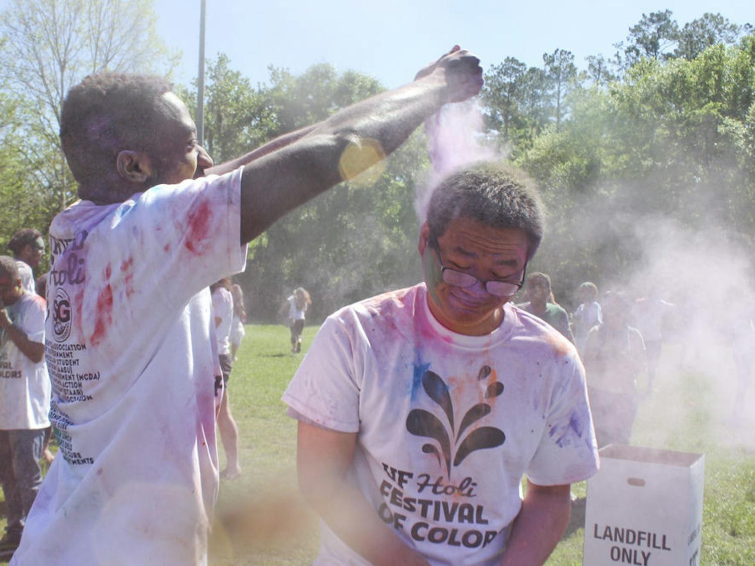 Sedlin Mirtil, a 26-year-old UF second-year pharmacy graduate student, dumps purple powder on Lin Teng, a 26-year-old UF second-year animal science graduate student, to celebrate the arrival of spring during UF Holi on Sunday.
