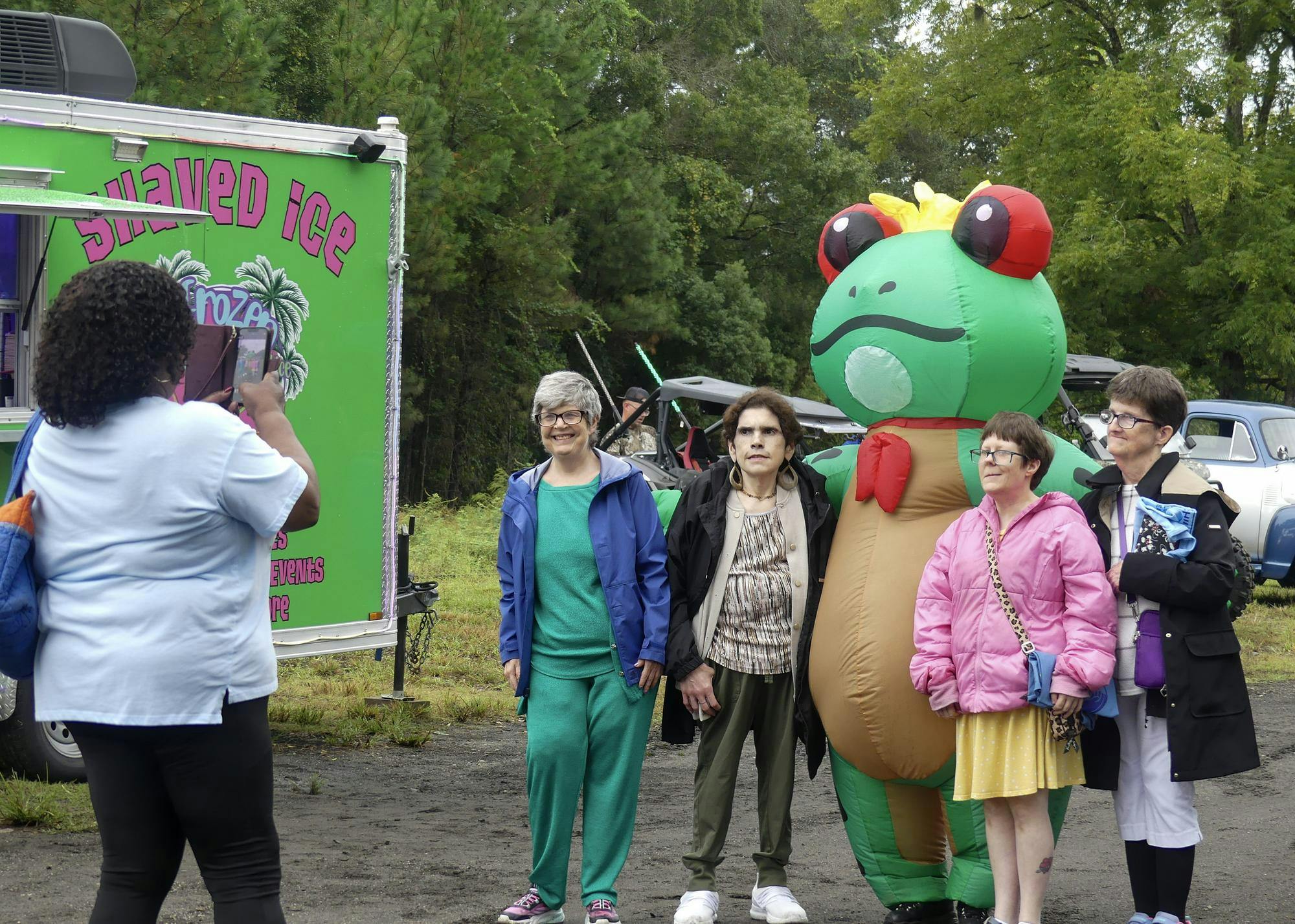 A group of customers take a photo with Frozen Frog Shaved Ice’s mascot during Waldo’s Third Annual Homecoming celebration on Saturday, Sept. 27, 2025, in Waldo, Fla.