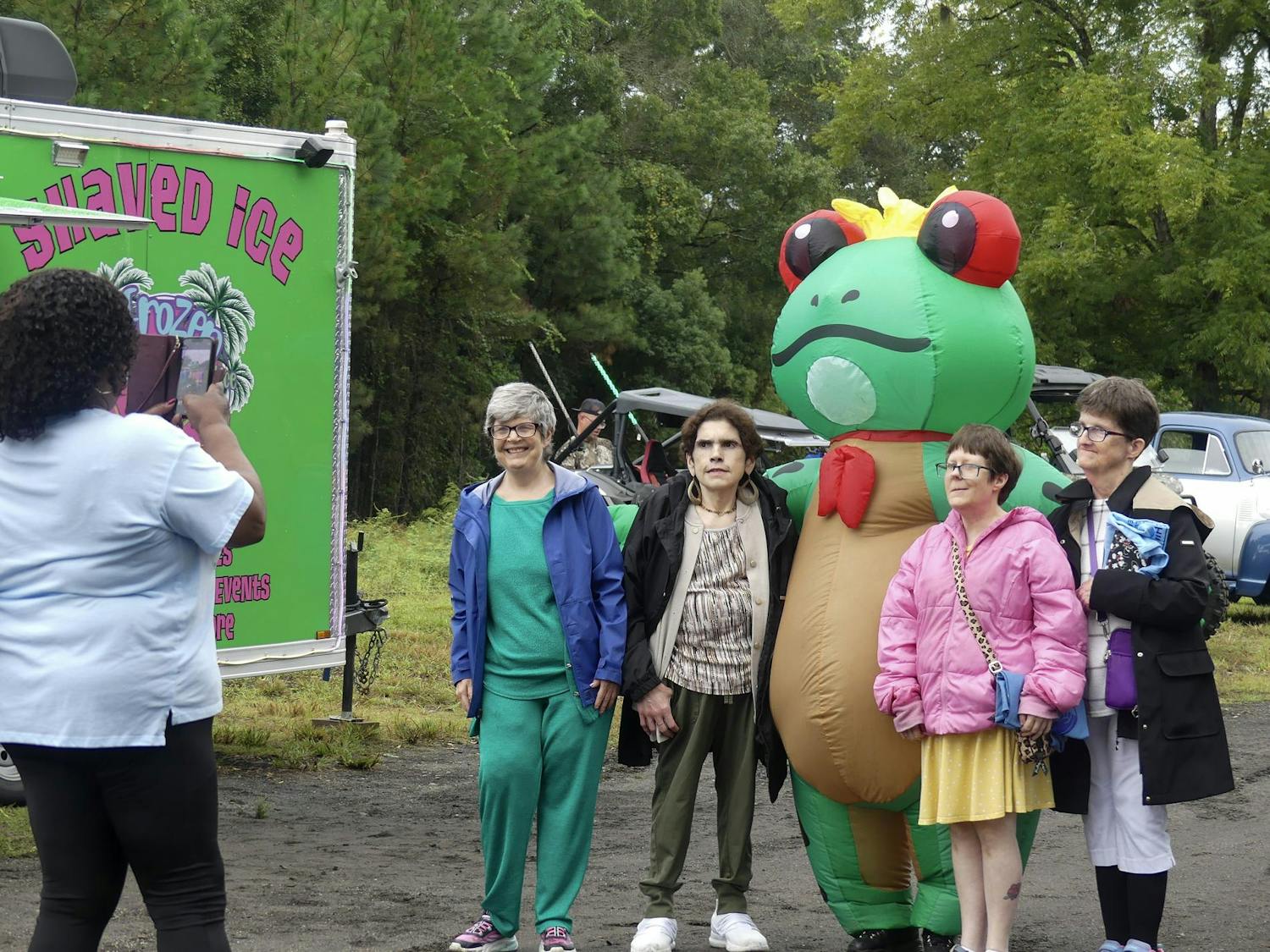A group of customers take a photo with Frozen Frog Shaved Ice’s mascot during Waldo’s Third Annual Homecoming celebration on Saturday, Sept. 27, 2025, in Waldo, Fla.