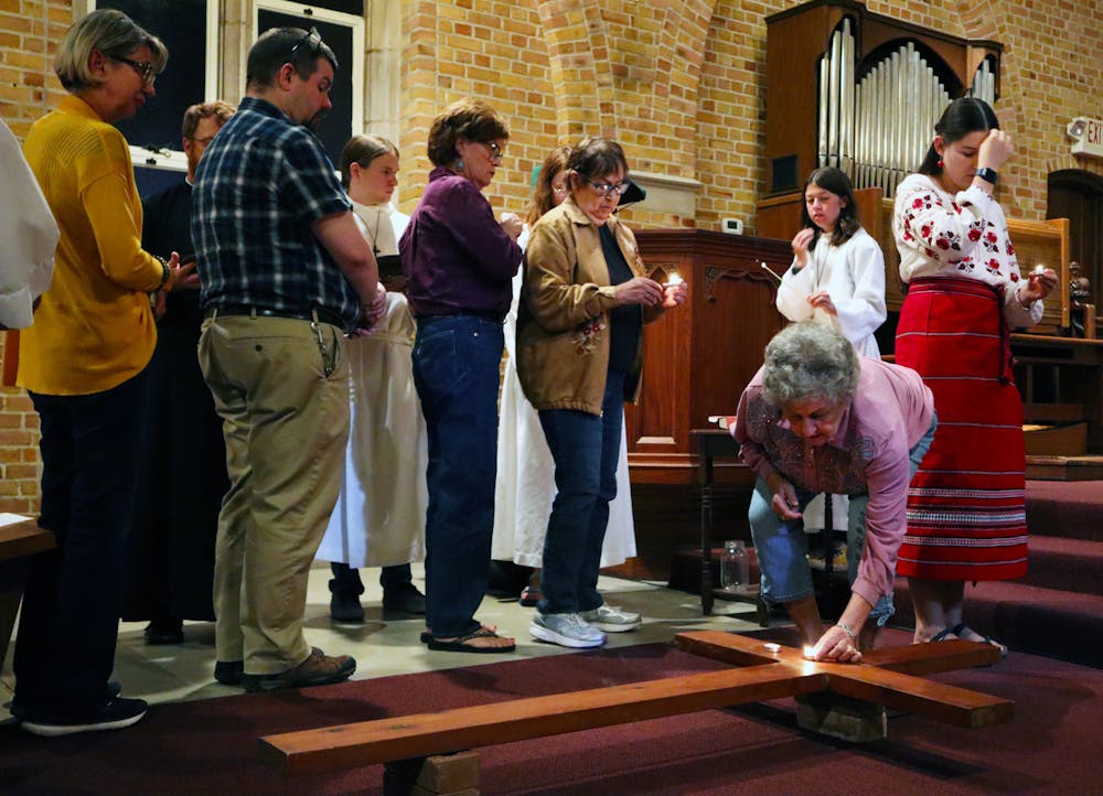 <p>Attendees at an ecumenial vigil for peace in Ukraine offer prayers around the cross at Chapel of the Incarnation Friday, Oct. 14, 2022.</p>