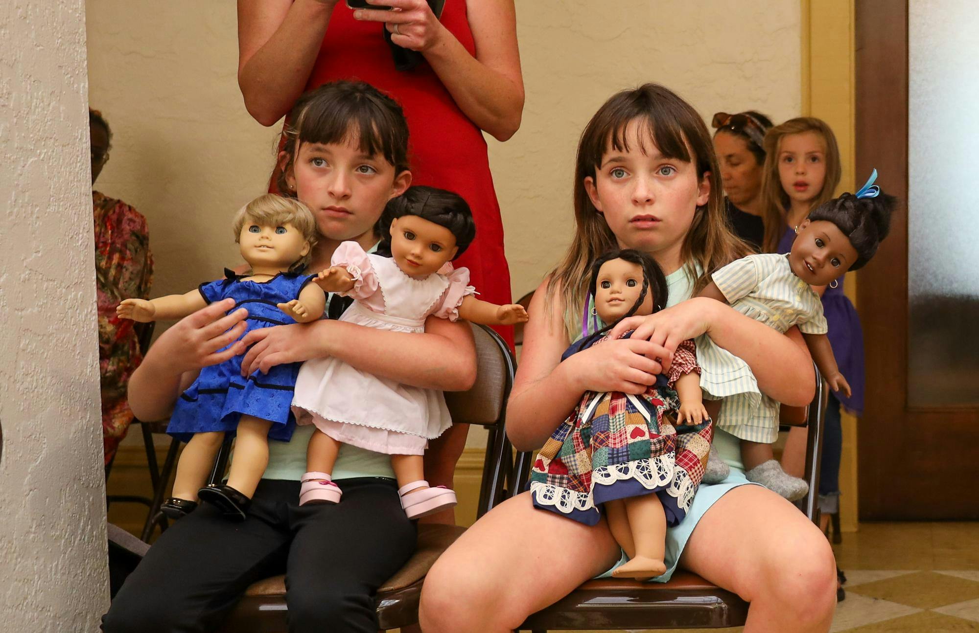 Justine (left) and Riley (right) hold their American Girl Dolls and watch a play at the Thomas Center in Gainesville, Fla., Saturday March 29, 2026.
