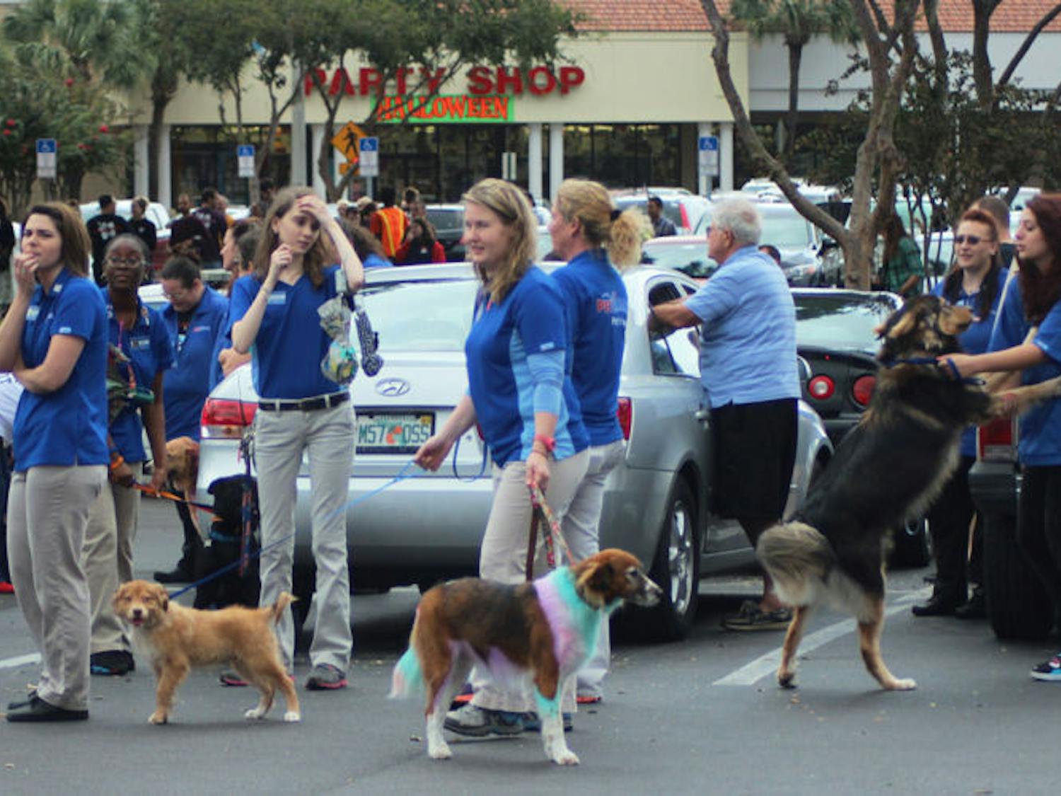 PetSmart employees and dogs stand in the parking lot after evacuating Monday while Gainesville Fire Rescue and Alachua County Fire Rescue work to extinguish the fire.