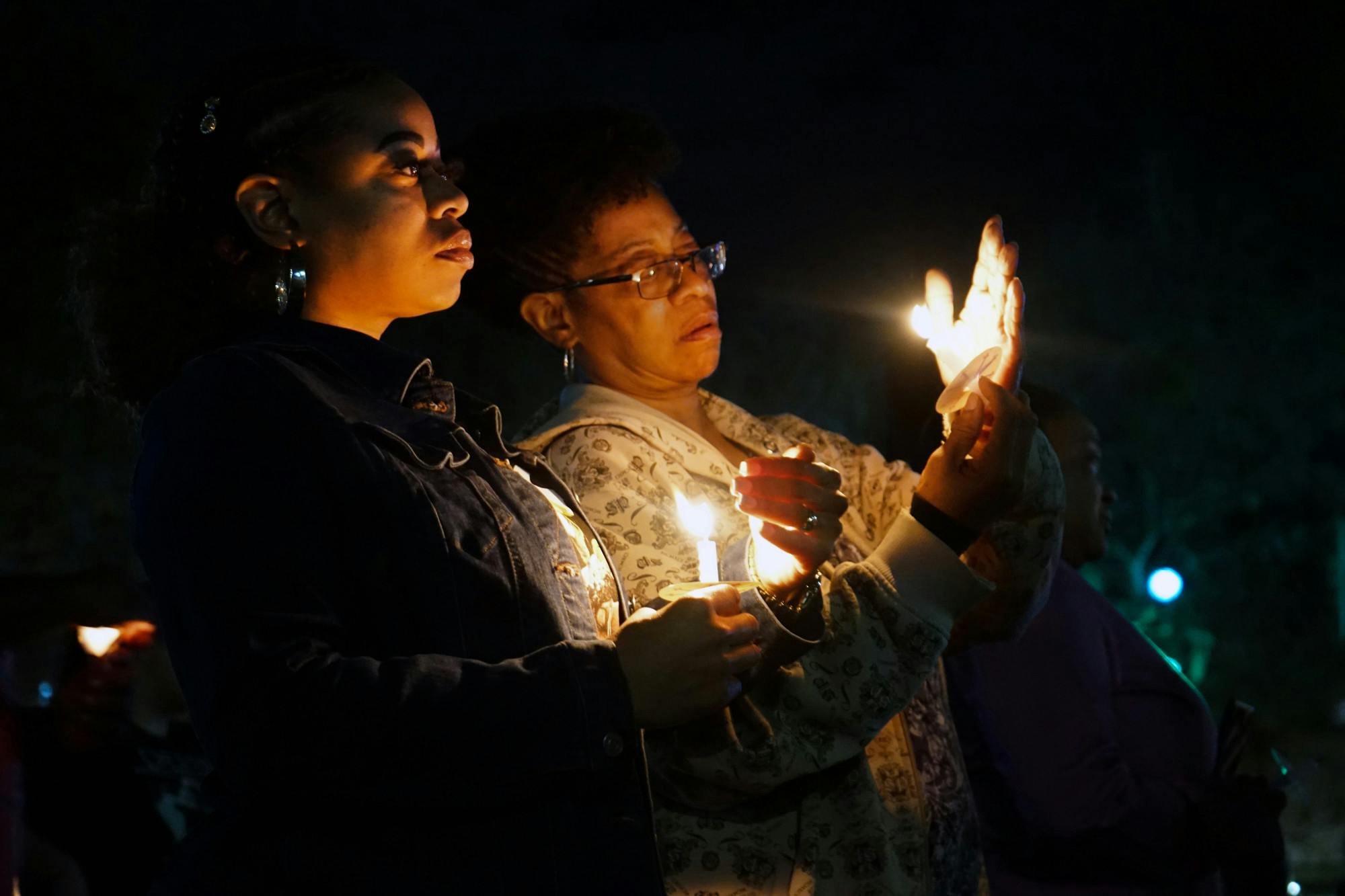 Two women attempt to keep their candles lit at a vigil held for Marcus Goodman, an inmate who died in the Alachua County Jail, at Bo Diddley Plaza Thursday, Feb. 2, 2023.