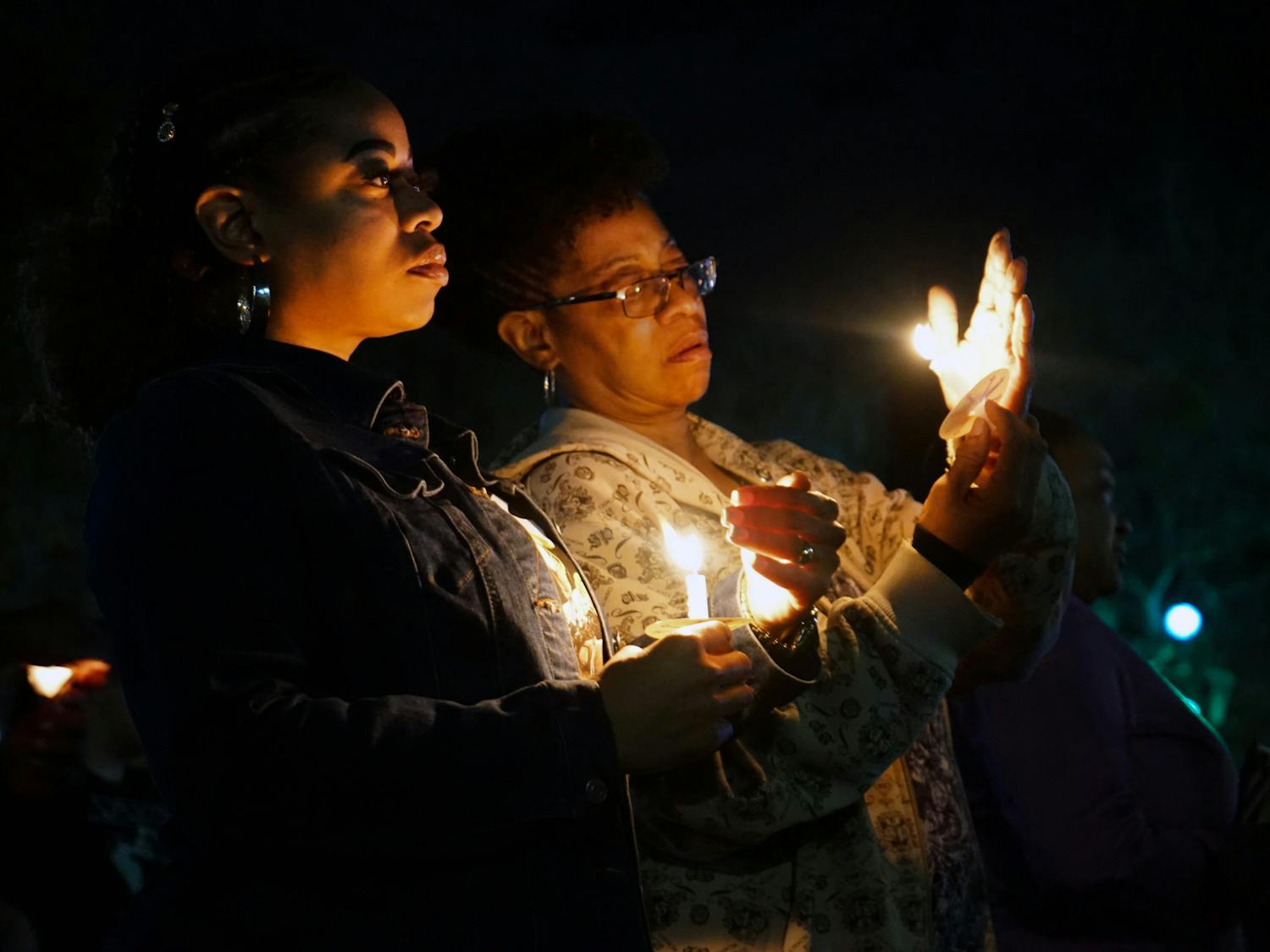 Two women attempt to keep their candles lit at a vigil held for Marcus Goodman, an inmate who died in the Alachua County Jail, at Bo Diddley Plaza Thursday, Feb. 2, 2023.