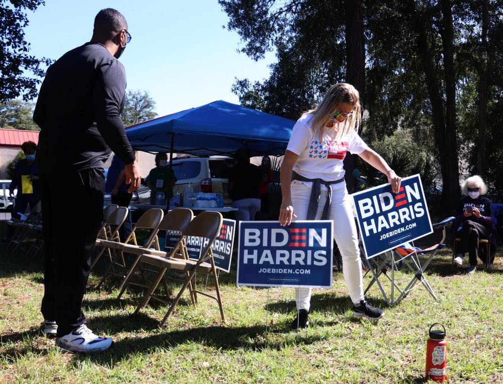 Cheree Padilla (right), a member of the Voter Protection Team, helps move the Biden campaign volunteers' signs on Tuesday, Nov. 3, 2020. The volunteers were told to move their signs and chairs to comply with the state statute that says no one can solicit voters within 150 feet of a polling location. (Lauren Witte/Alligator Staff)