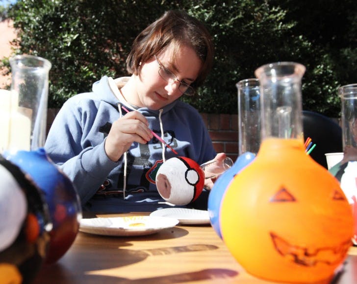 Courtney Ligon, 20, a biochemistry sophomore, paints a Pokemon-inspired pokeball flask Tuesday for a fundraiser for the UF Chemistry Club on Turlington Plaza.