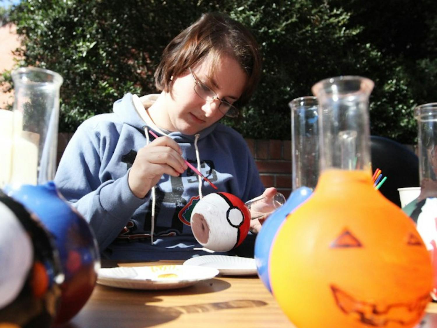 Courtney Ligon, 20, a biochemistry sophomore, paints a Pokemon-inspired pokeball flask Tuesday for a fundraiser for the UF Chemistry Club on Turlington Plaza.