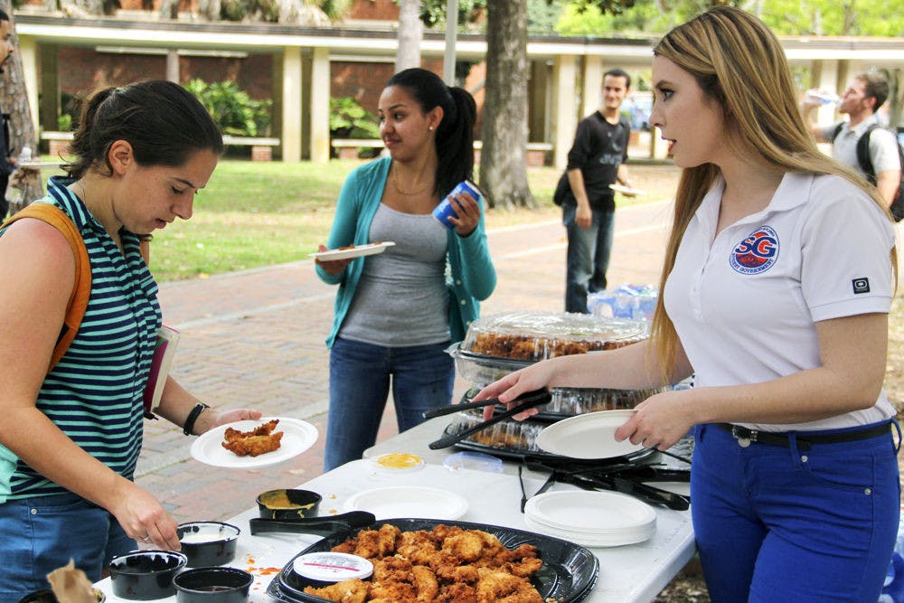 Gabrielle Beecher, a 20-year-old UF journalism and marketing sophomore and the director of research of Action SG, serves Chick-fil-A to Missy Olguin (left), a 21-year-old UF biology junior, as part of Student Government's Lunch on the Lawn event on the Plaza of the Americas on Thursday afternoon. The event was a way for SG to hear students' opinions and answer their questions.