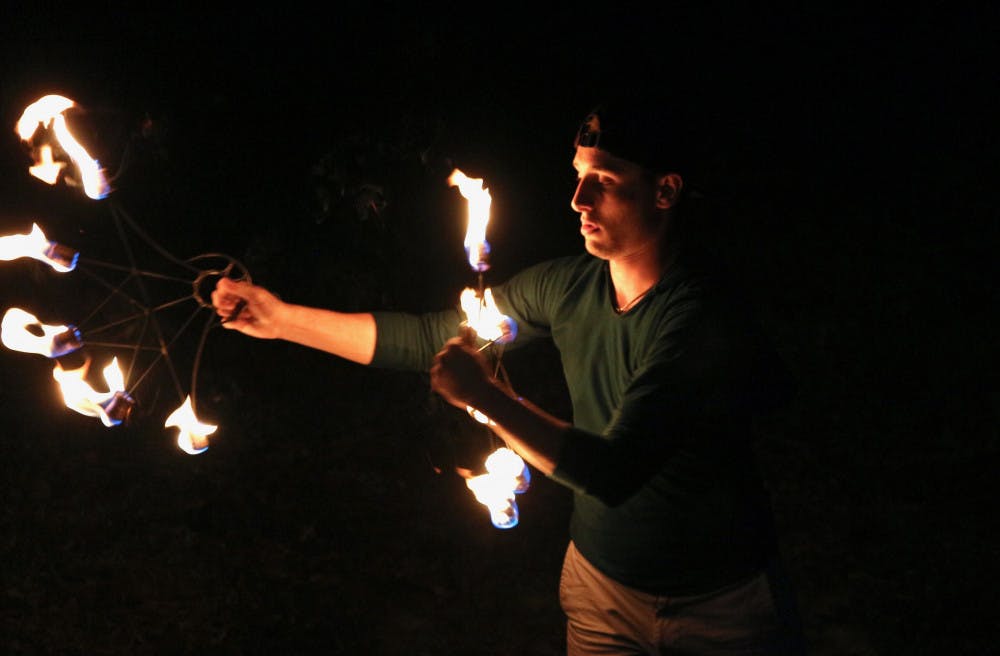 <p>Sam Konchan, 21, UF botany junior spins a set of fire fans in the backyard area of Flow Space located on 117 NW 16th Ave. Spinning fire is only one form of the flow arts in which Konchan also finds a community offering lifelong friendships.</p>