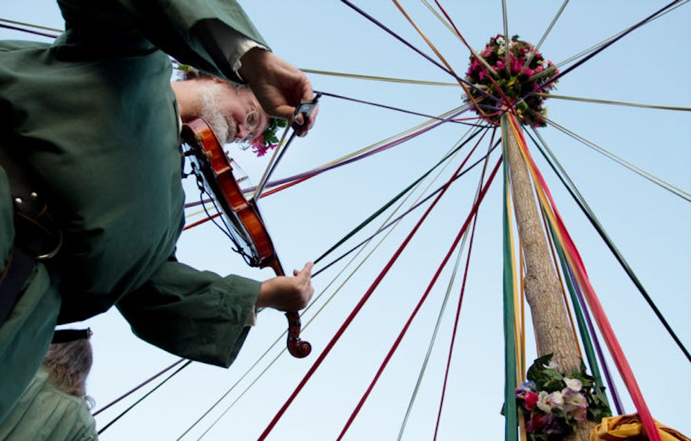 <p>Richard Crew plays the violin underneath a maypole at the Hoggetowne Medieval Faire on Sunday. Crew is part of the Greenwood Morris dance group, a group that organizes dances and plays under the maypole. He said he has been playing the violin and attending various medieval fairs for about 20 years.</p>