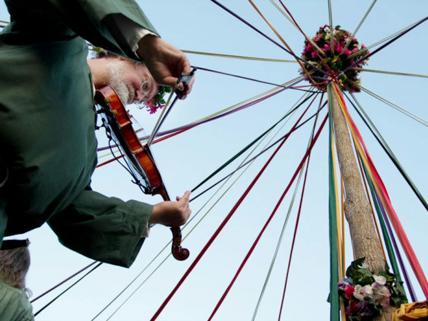 Richard Crew plays the violin underneath a maypole at the Hoggetowne Medieval Faire on Sunday. Crew is part of the Greenwood Morris dance group, a group that organizes dances and plays under the maypole. He said he has been playing the violin and attending various medieval fairs for about 20 years.