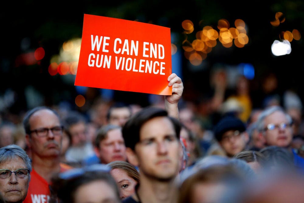 Mourners gather for a vigil at the scene of a mass shooting, Sunday, Aug. 4, 2019, in Dayton, Ohio. A masked gunman in body armor opened fire early Sunday in the popular entertainment district in Dayton, killing several people, including his sister, and wounding dozens before he was quickly slain by police, officials said. (AP Photo/John Minchillo