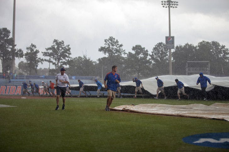 Members of Florida's grounds crew place a tarp over the infield during the rain delay in UF's 5-2 loss to UNC on Saturday at McKethan Stadium. The Tar Heels scored all five of their runs in the inning following the rain delay, which lasted more than three hours.