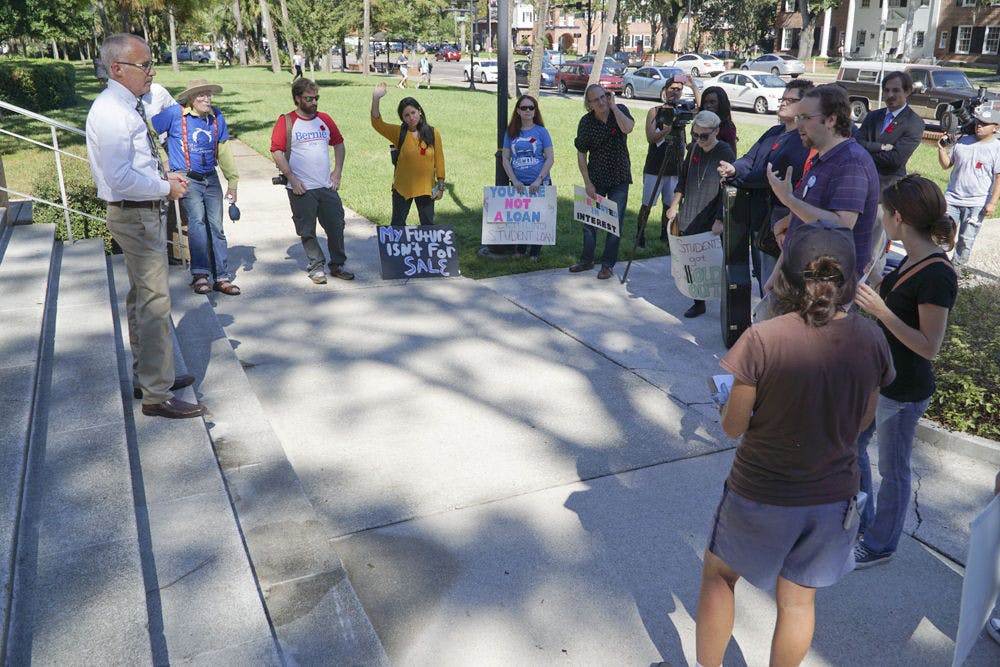<p>UF spokesman Steve Orlando (left) addresses about a dozen protesters participating in the nationwide Million Student March outside Tigert Hall on Nov. 12, 2015. Students and Gainesville locals protested rising tuition, loan debt and low-wage jobs offered to them after leaving school.</p>