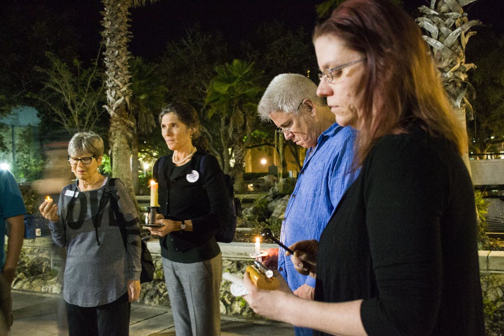 Dari Smith and Wes Wheeler hold candles as Catherine Cake hits a chime 26 times to remember the victims of Sunday’s shooting in Sutherland Springs, Texas.