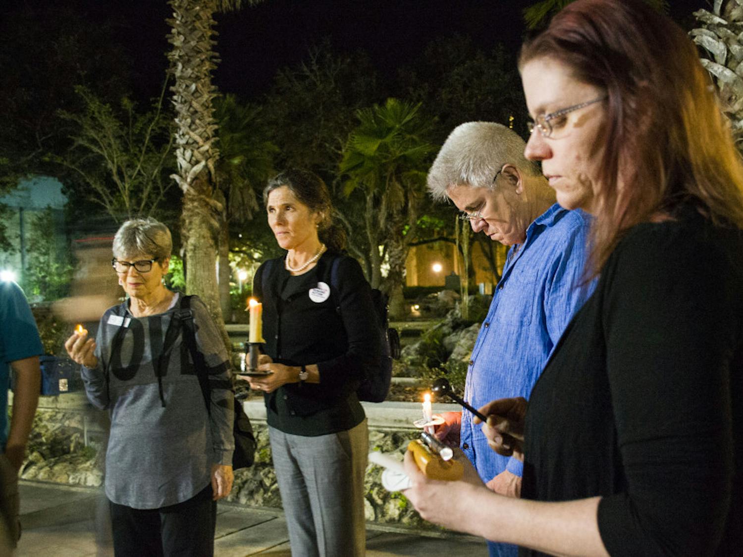 Dari Smith and Wes Wheeler hold candles as Catherine Cake hits a chime 26 times to remember the victims of Sunday’s shooting in Sutherland Springs, Texas.
