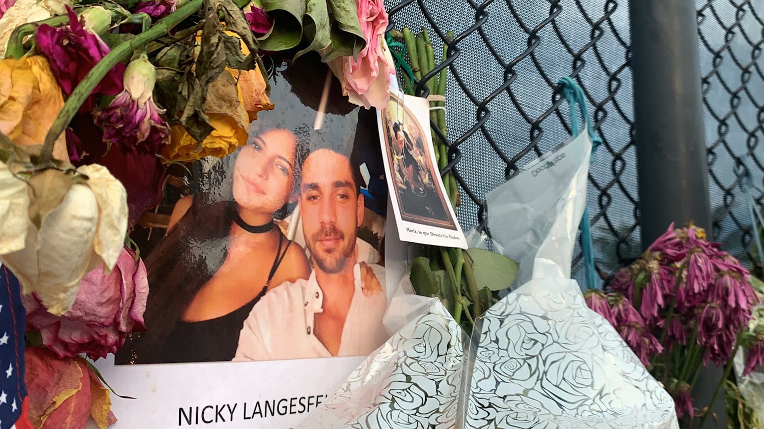 A photo of Nicole "Nicky" Langesfeld and Luis Sadovnic hangs on a memorial wall in Surfside, Florida on Saturday, July 3, 2021. Langesfeld and Sadovnic are two UF alumni among the more than 100 people still unaccounted for after the partial collapse of the Champlain Towers South building on June 24. 