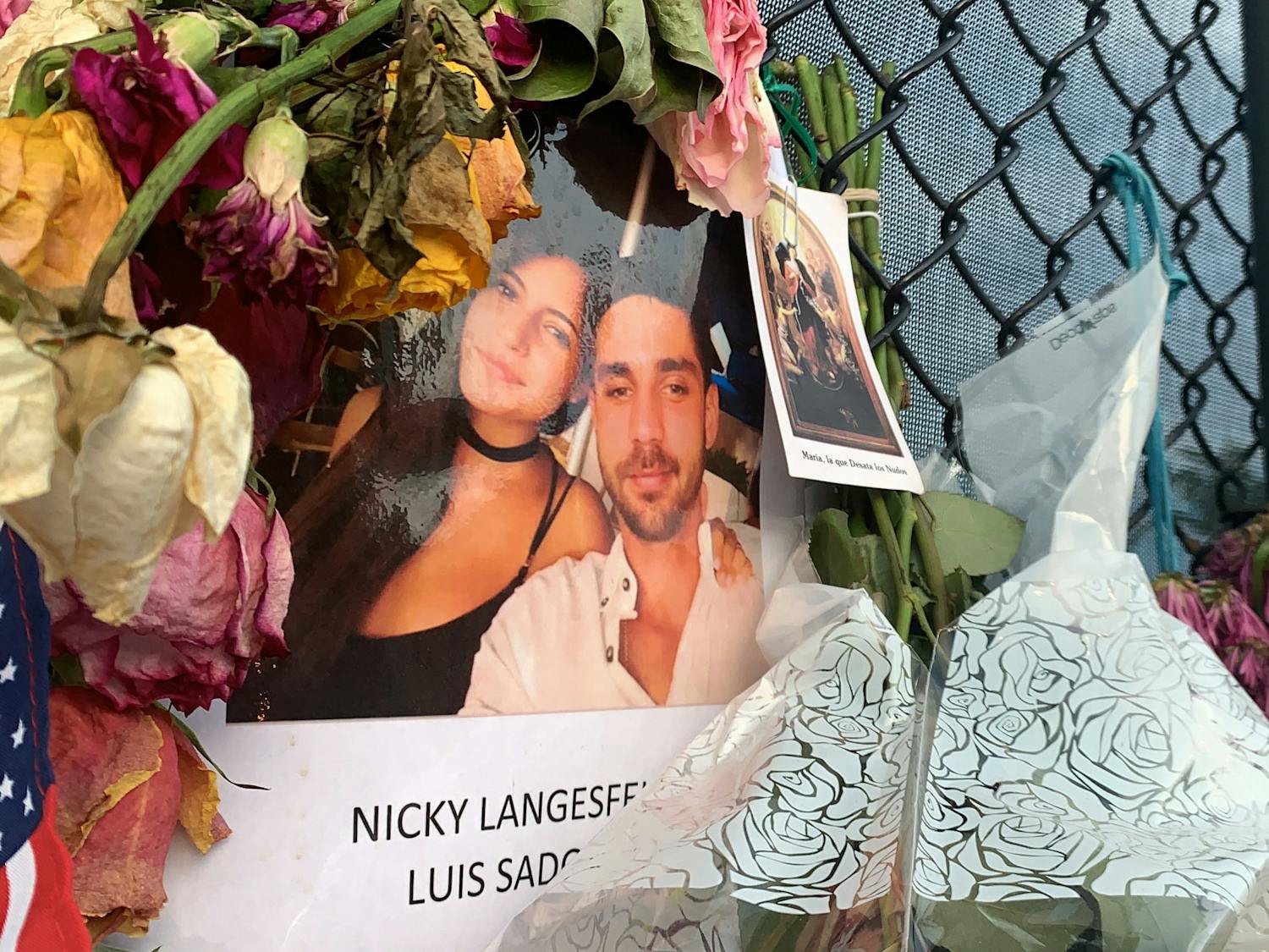 A photo of Nicole "Nicky" Langesfeld and Luis Sadovnic hangs on a memorial wall in Surfside, Florida on Saturday, July 3, 2021. Langesfeld and Sadovnic are two UF alumni among the more than 100 people still unaccounted for after the partial collapse of the Champlain Towers South building on June 24. 