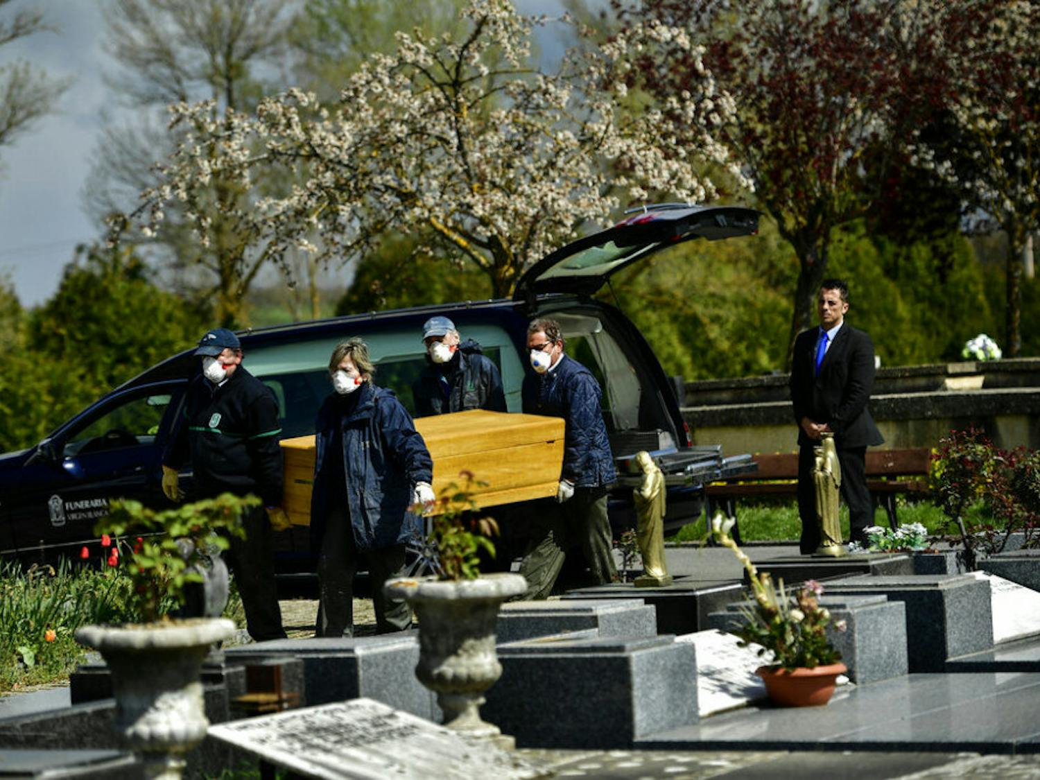 Undertakers wearing protection masks to protect from the coronavirus, carry a coffin to a burial at Salvador cemetery during the coronavirus outbreak, near to Vitoria, northern Spain, Monday, March 30, 2020. The new coronavirus causes mild or moderate symptoms for most people, but for some, especially older adults and people with existing health problems, it can cause more severe illness or death. (AP Photo/Alvaro Barrientos)