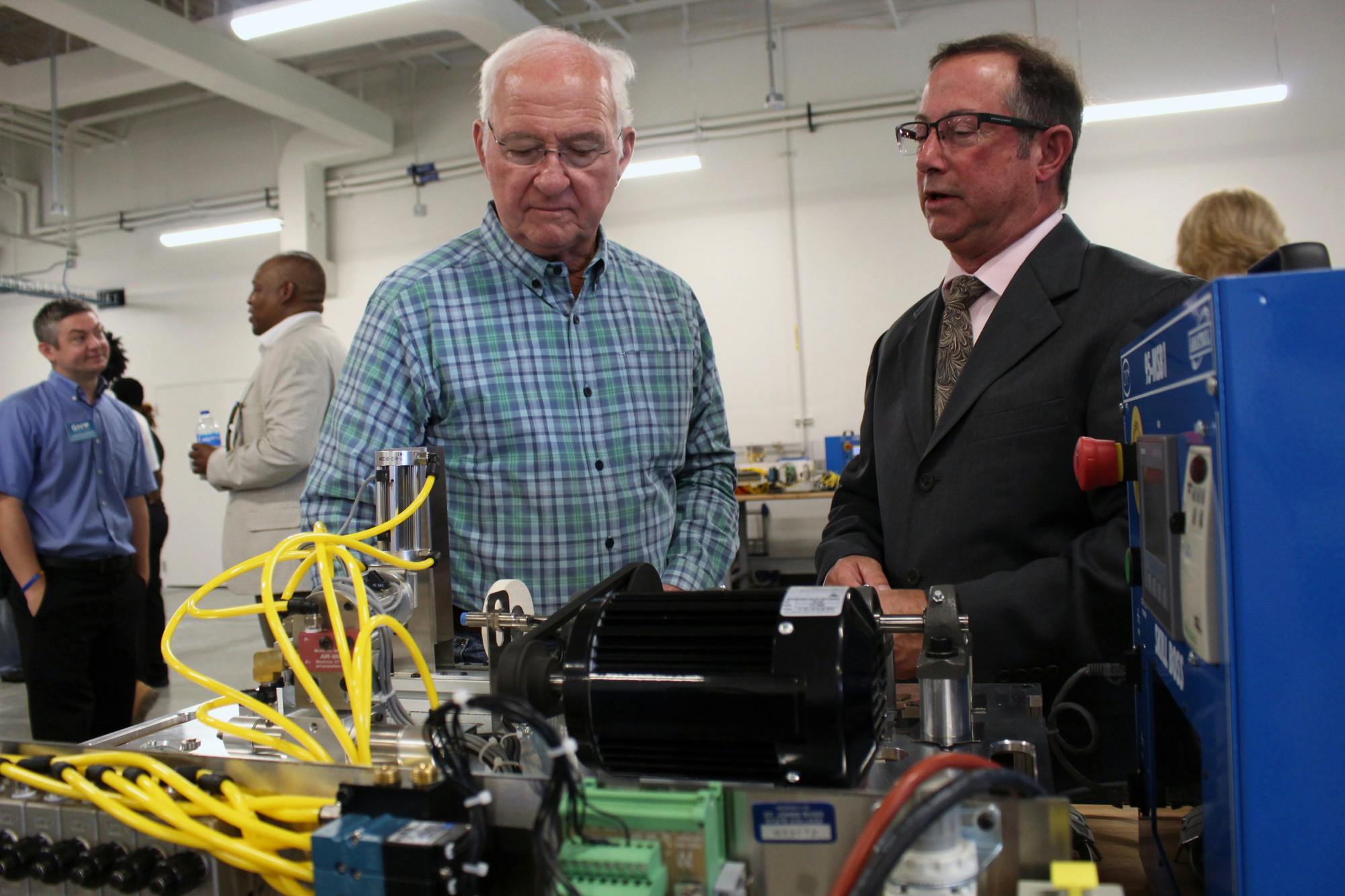 Jim Emerson (right) listens as Professor Mark Terrone (left) explains one of the displays at the open house for the Ralph W. Cellon Jr. Institute for Skilled Trades and Advanced Manufacturing on Tuesday, August 19, 2025.