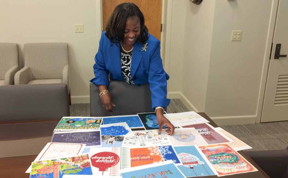 Florida Bridgewater-Alford, the chair of the Holiday Greeting Card Contest advisory committee, organizes the dozens of artwork entries submitted by UF students for President Kent Fuchs and his wife’s greeting card contest.