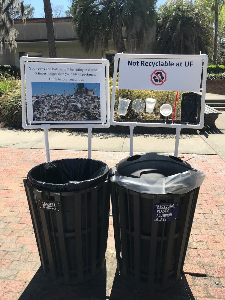 Pictured is a pair signs framed by PVC pipes hanging next to a set of trash and recycling cans that appeared on campus early Monday morning. The signs are part of a student research project by UF/IFAS first-year PhD student Amanda Brinton. The signs will be up until April 20, she said.