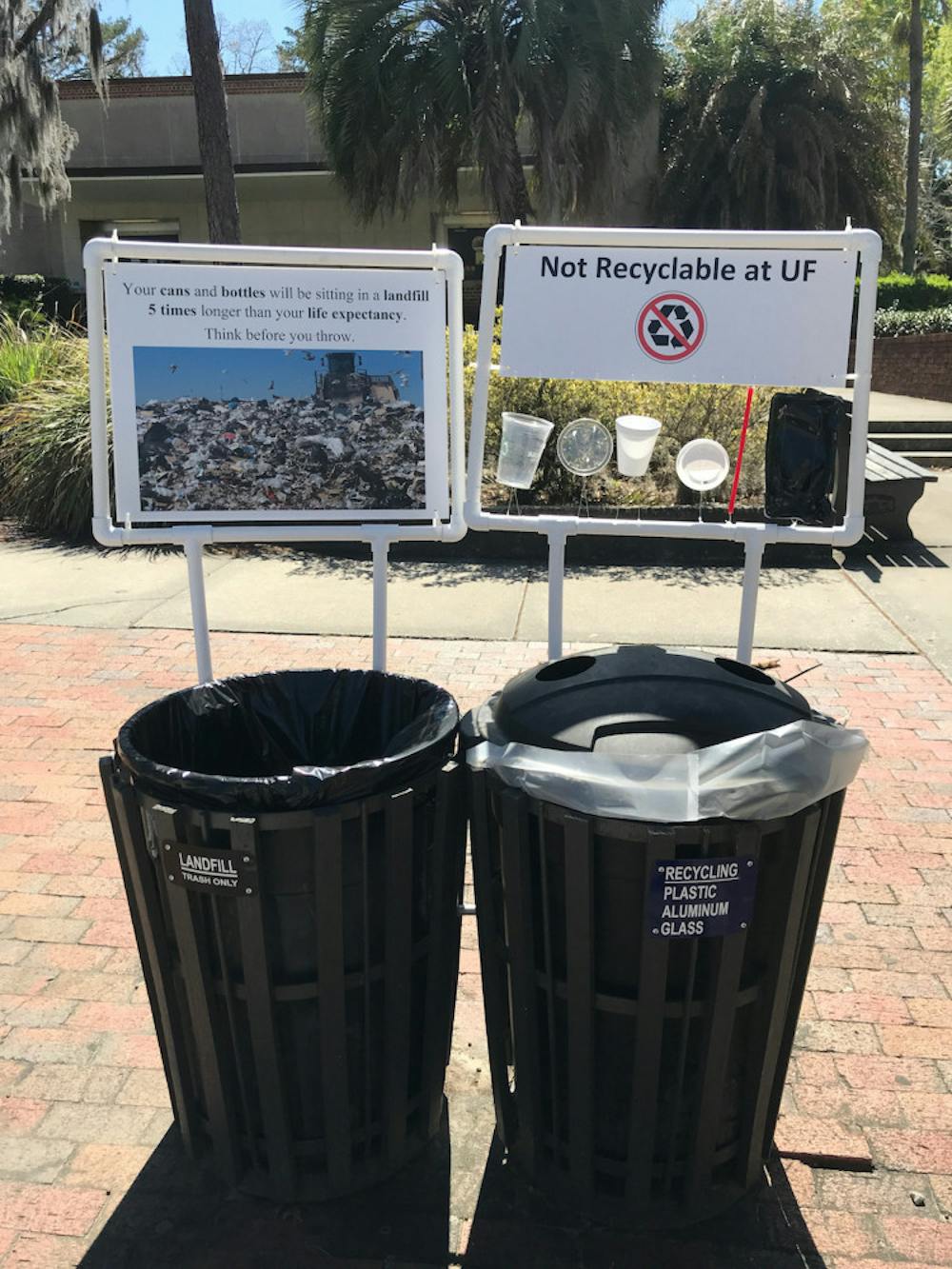 <p>Pictured is a pair signs framed by PVC pipes hanging next to a set of trash and recycling cans that appeared on campus early Monday morning. The signs are part of a student research project by UF/IFAS first-year PhD student Amanda Brinton. The signs will be up until April 20, she said.</p>