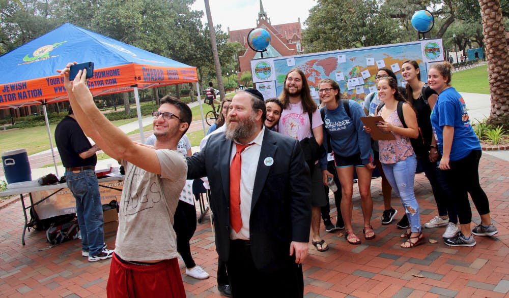 Tyler Ellman, a 22-year-old UF theatre fifth year, and Rabbi Berl Goldman, 46, take a selfie with students participating in the Good Deed Marathon on the Plaza of the Americas.