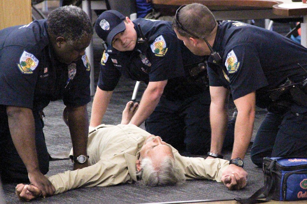 UPD officers respond to a call about trespasser David Lee Patterson in Library West on Monday afternoon. Patterson had a medical episode as he was about to be arrested and was later transported to the Malcolm Randall VA Medical Center. See the story pg. 4.