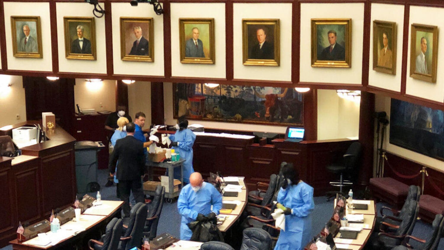 Crew members swab down Florida's House floor at the state Capitol in Tallahassee, Fla., Monday, March 9, 2020, after several members voluntarily submitted themselves for testing of a new strain of coronavirus. The Florida House abruptly recessed Monday afternoon and cleared public galleries after several of its members agreed to be tested for the new strain of coronavirus after recently attending a political event in Washington where one attendee tested positive for COVID-19. (AP Photo/Bobby Caina Calvan)