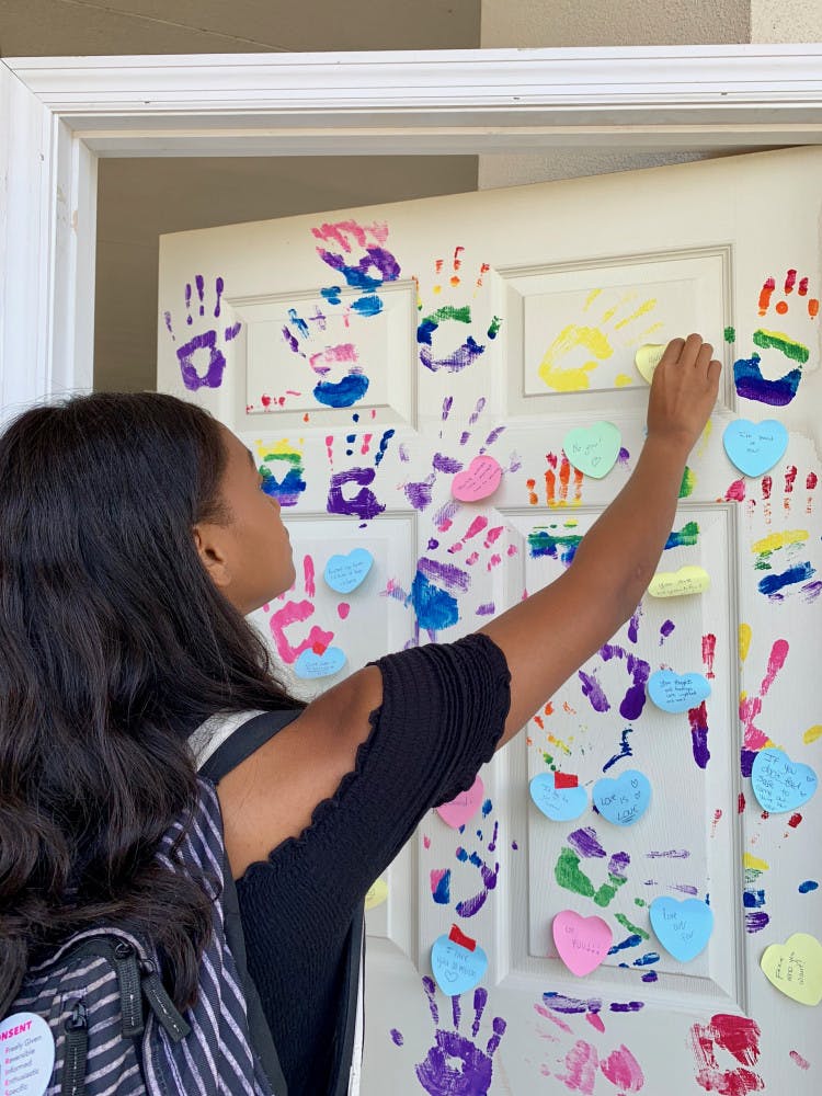 Kamya Bates, a 19-year-old UF marine science freshman, places a sticky note on a door in front of the Reitz Union during a National Coming Out Day celebration.