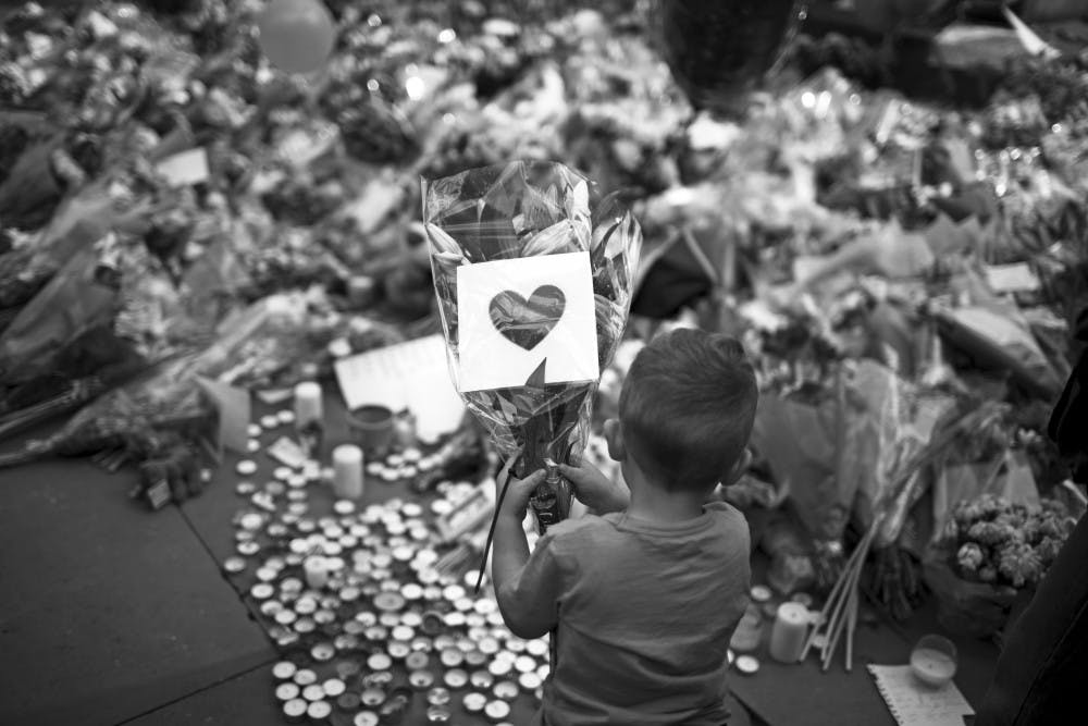 A child places flowers in a square in central Manchester, England, on Wednesday after the suicide bomb attack at an Ariana Grande concert that left 22 people dead and many more injured as it ended on Monday night at the Manchester Arena. 
