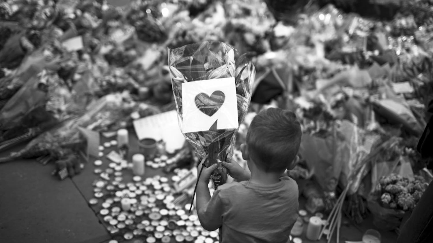 A child places flowers in a square in central Manchester, England, on Wednesday after the suicide bomb attack at an Ariana Grande concert that left 22 people dead and many more injured as it ended on Monday night at the Manchester Arena. 