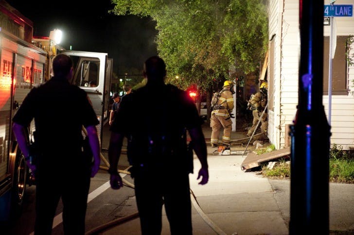 Gainesville Police officers look on as Gainesville Fire Rescue workers enter a building on the 400 block of Northwest 13th Street late Tuesday night.