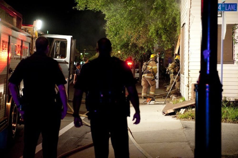 <p>Gainesville Police officers look on as Gainesville Fire Rescue workers enter a building on the 400 block of Northwest 13th Street late Tuesday night.</p>